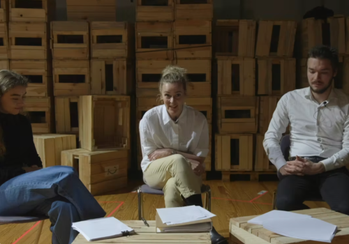 tre personer sitter ved et bord manus foran