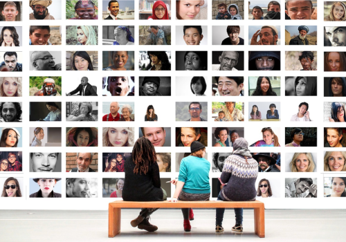 tre personer sitter foran bilde av mange personer